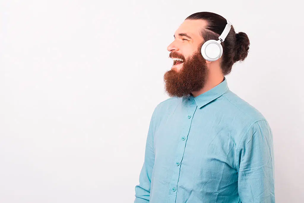 Hymyilevä mies kuulokkeet päässä valkoista taustaa vasten