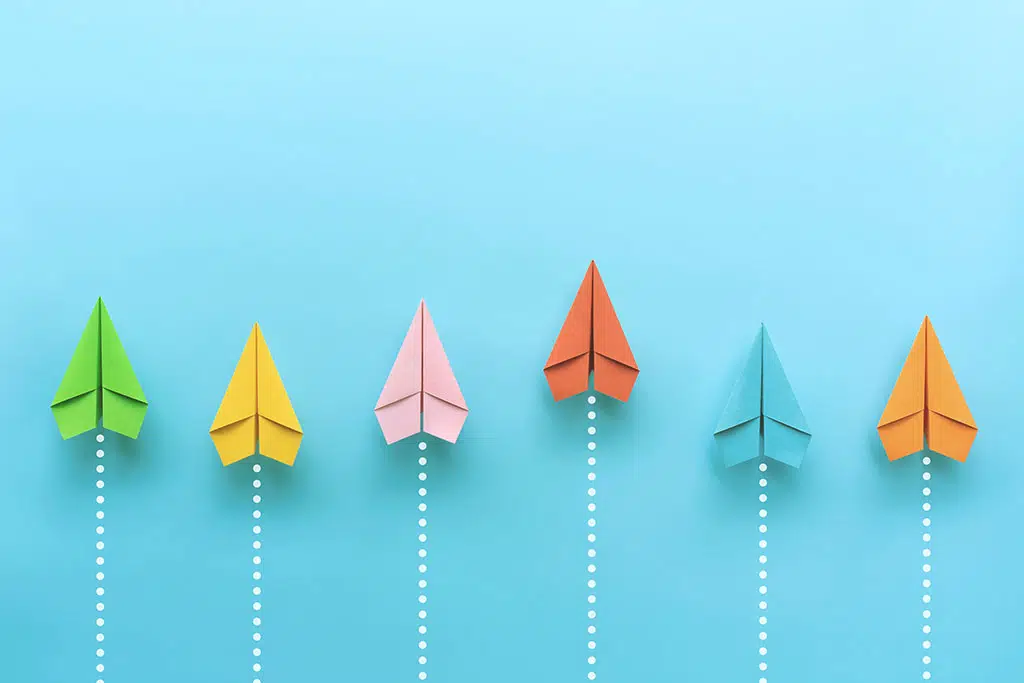 Värikkäät paperilennokit sinisellä taustalla